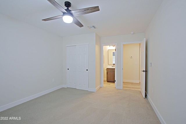 unfurnished bedroom with light carpet, a closet, ensuite bathroom, and ceiling fan