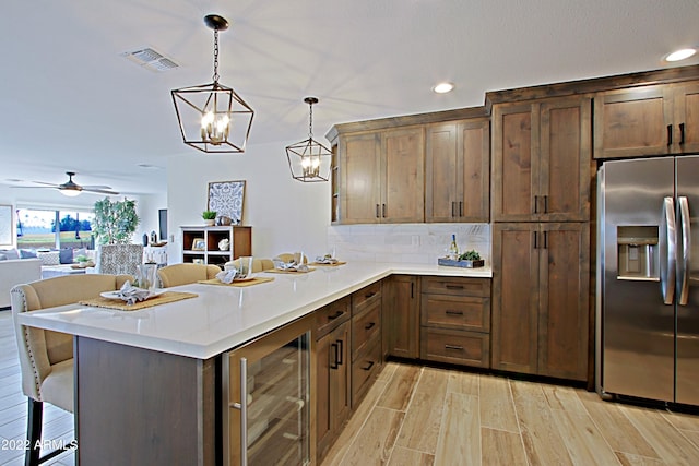 kitchen featuring kitchen peninsula, stainless steel fridge, beverage cooler, backsplash, and light hardwood / wood-style floors