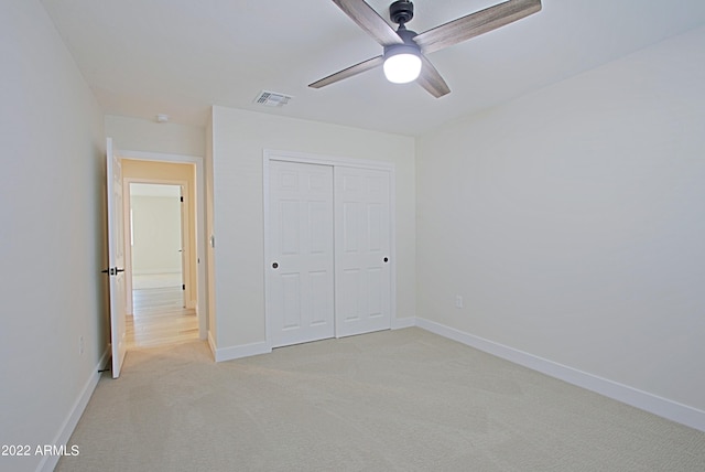 unfurnished bedroom featuring light carpet, a closet, and ceiling fan