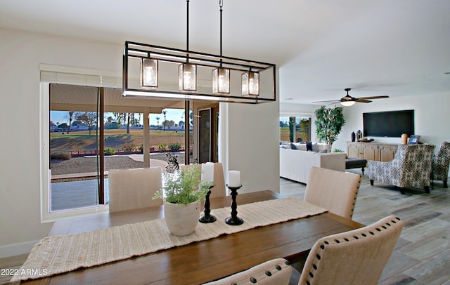 dining space featuring light wood-type flooring and ceiling fan with notable chandelier