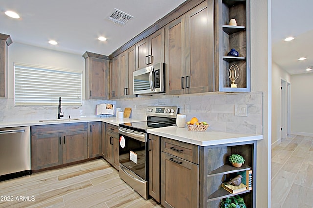 kitchen with backsplash, appliances with stainless steel finishes, light hardwood / wood-style flooring, dark brown cabinetry, and sink