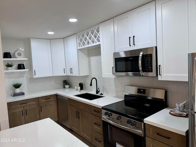 kitchen with tasteful backsplash, white cabinetry, sink, and stainless steel appliances