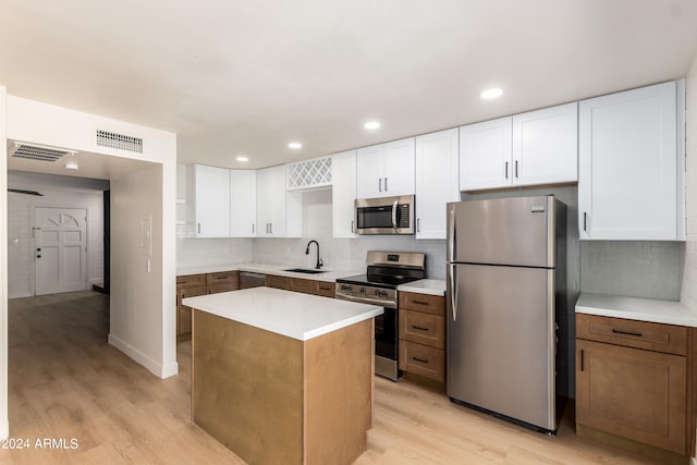 kitchen featuring decorative backsplash, a kitchen island, appliances with stainless steel finishes, and light hardwood / wood-style flooring