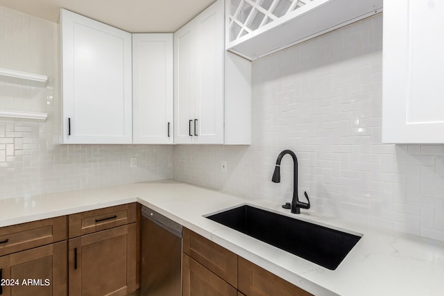 kitchen featuring decorative backsplash, light stone countertops, stainless steel dishwasher, sink, and white cabinets