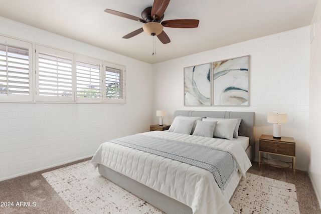 bedroom with ceiling fan, light colored carpet, and brick wall