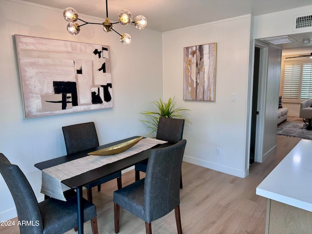 dining room featuring light wood-type flooring, ornamental molding, and a chandelier