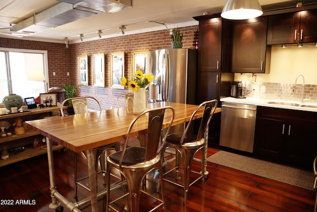 kitchen featuring sink, brick wall, dark hardwood / wood-style floors, and appliances with stainless steel finishes