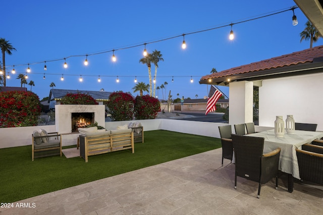 patio at twilight featuring an outdoor living space with a fireplace and a yard