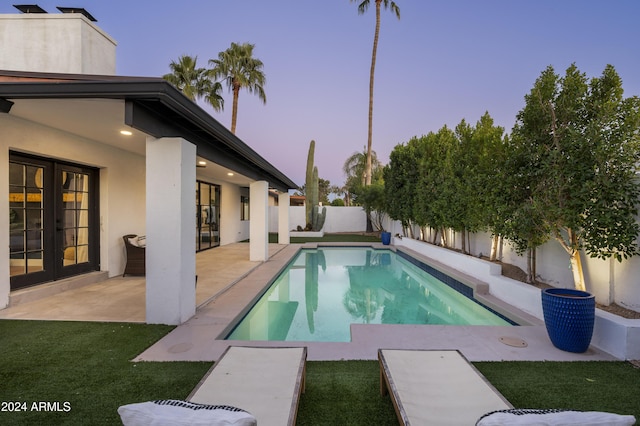 pool at dusk with a patio and french doors