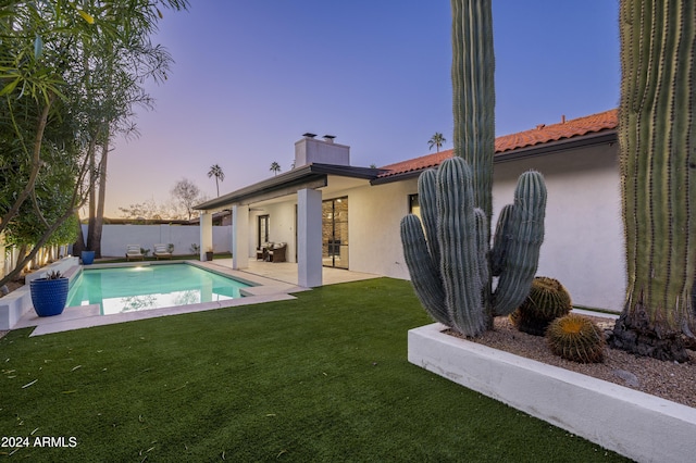 pool at dusk with a yard and a patio area