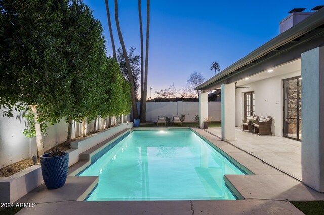 pool at dusk featuring a patio