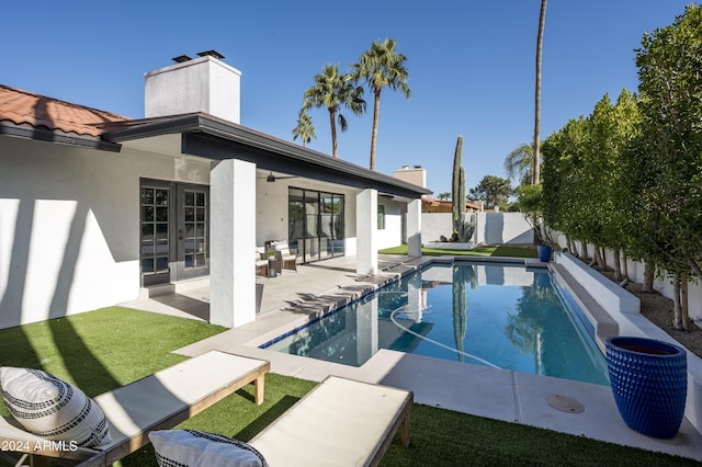 view of pool featuring french doors, ceiling fan, a patio area, and a lawn