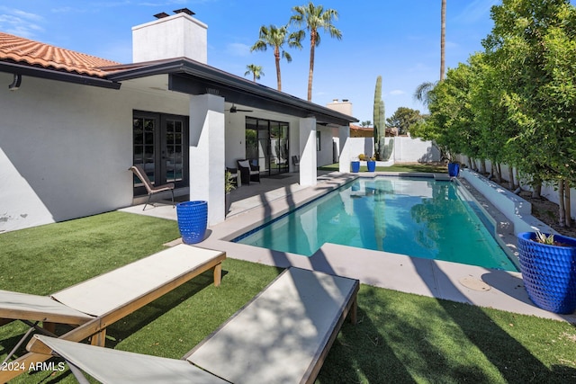 view of swimming pool featuring a lawn, ceiling fan, and a patio