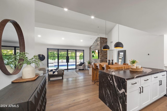 kitchen with white cabinetry, a center island, high vaulted ceiling, pendant lighting, and light wood-type flooring