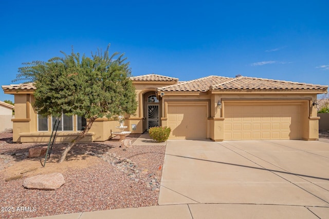 mediterranean / spanish-style house with stucco siding, a garage, concrete driveway, and a tiled roof