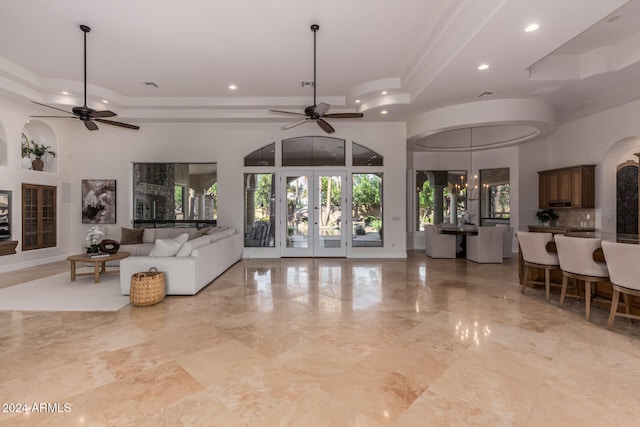 living room with ceiling fan with notable chandelier and a high ceiling