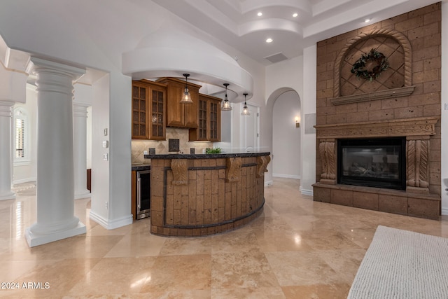 bar with a fireplace, beverage cooler, decorative columns, pendant lighting, and decorative backsplash