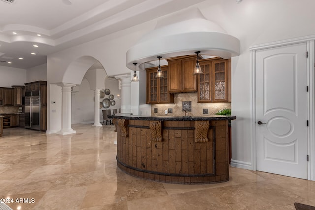 bar featuring decorative columns, hanging light fixtures, backsplash, and high end refrigerator