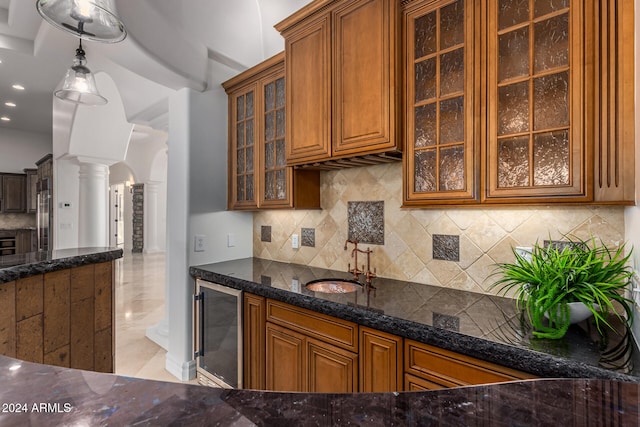 kitchen with wine cooler, backsplash, decorative light fixtures, sink, and decorative columns