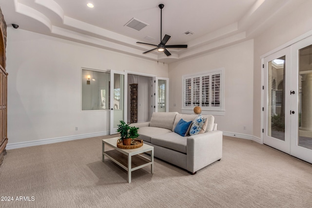 living room with french doors, light colored carpet, ceiling fan, and a raised ceiling