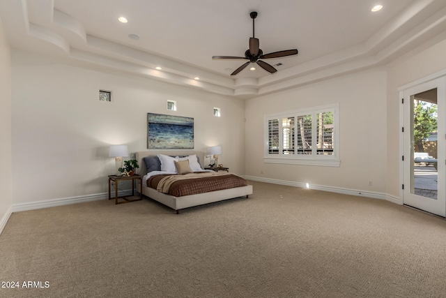 bedroom featuring ceiling fan, access to exterior, multiple windows, and a raised ceiling