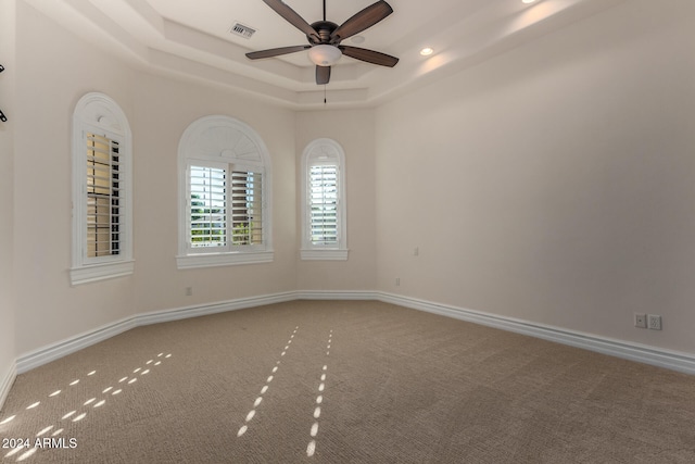 carpeted spare room with ceiling fan and a tray ceiling