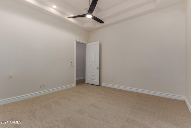 unfurnished room featuring light colored carpet, ceiling fan, and a raised ceiling