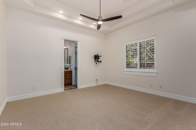 unfurnished room with ceiling fan, a raised ceiling, and carpet floors