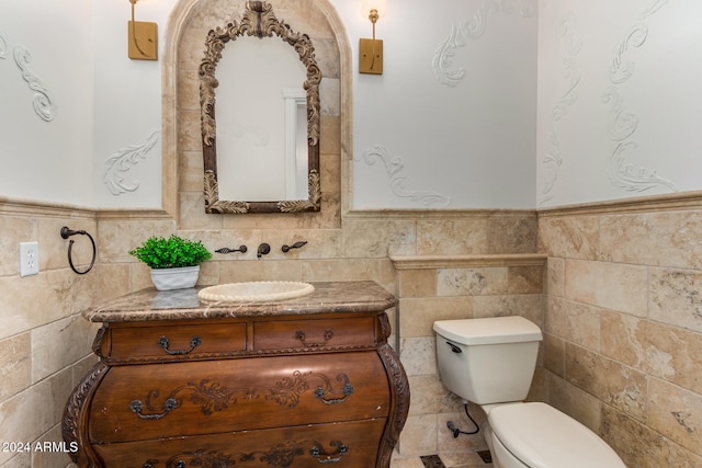 bathroom featuring vanity, toilet, and tile walls