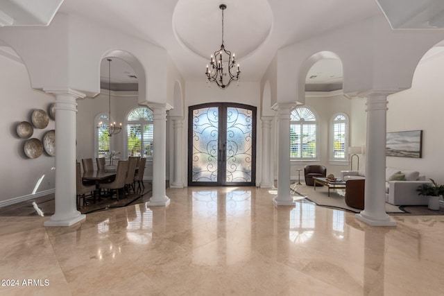 entrance foyer featuring a high ceiling, an inviting chandelier, french doors, and a tray ceiling