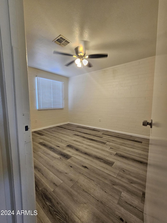 empty room with a textured ceiling, wood-type flooring, and ceiling fan