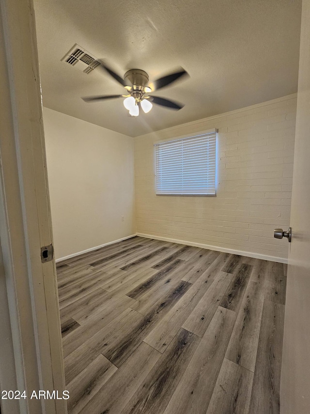 spare room with hardwood / wood-style flooring, ceiling fan, and a textured ceiling