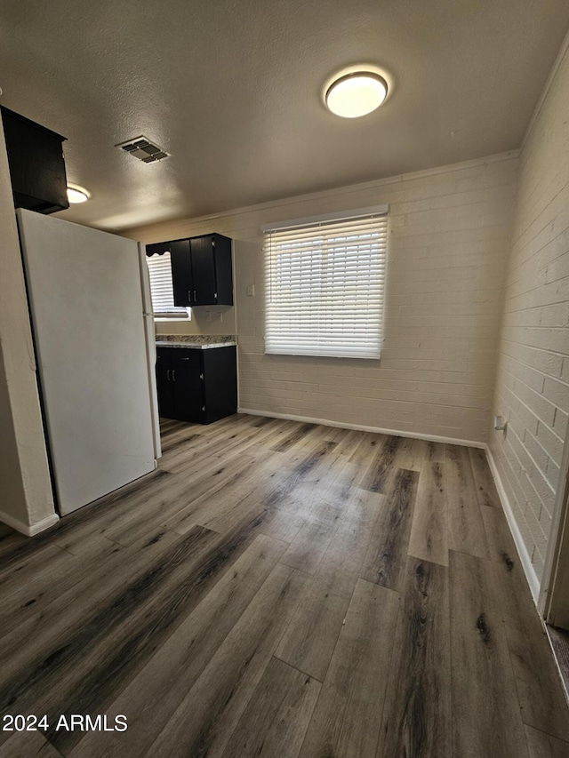 interior space featuring brick wall, dark wood-type flooring, and a textured ceiling