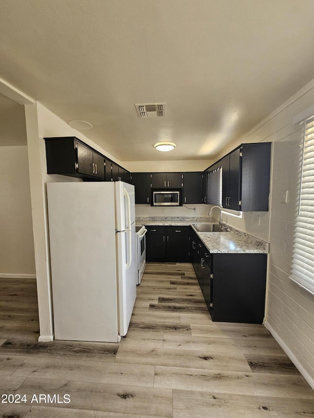 kitchen featuring light stone countertops, sink, white appliances, and light hardwood / wood-style floors