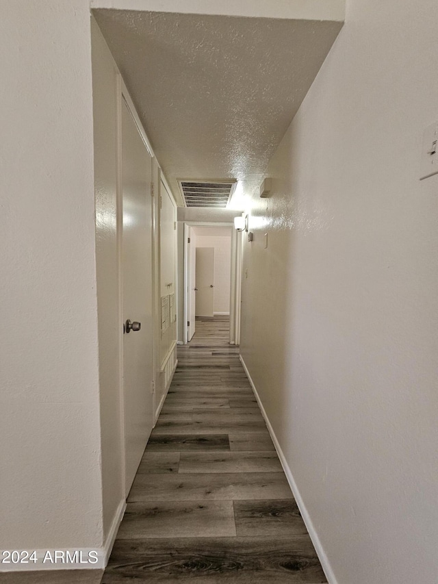 corridor with dark hardwood / wood-style flooring and a textured ceiling