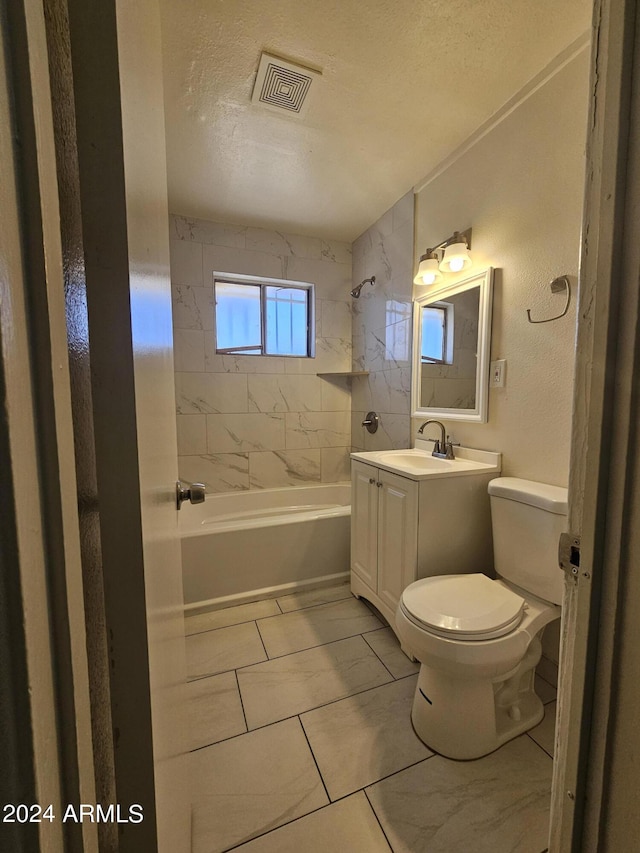 full bathroom with vanity, a textured ceiling, toilet, and tiled shower / bath