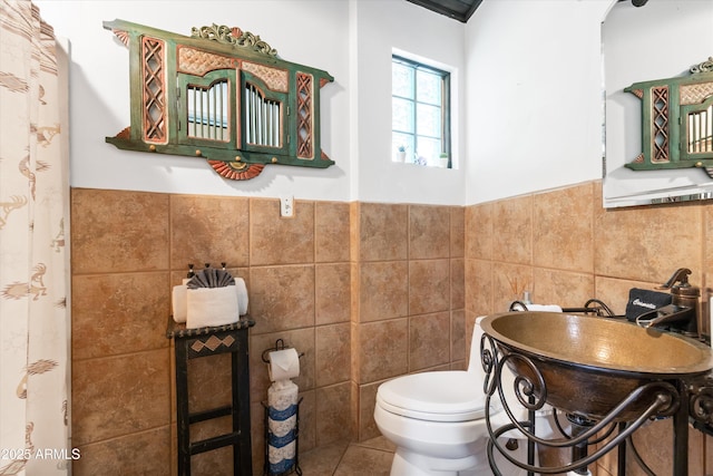 bathroom with tile walls, sink, tile patterned flooring, and toilet