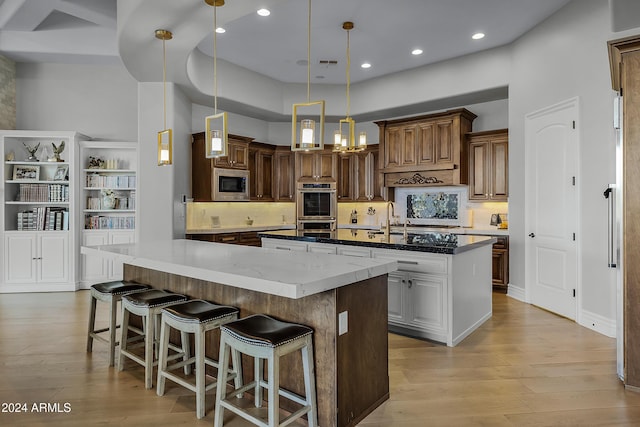 kitchen featuring dark stone counters, a large island, pendant lighting, and appliances with stainless steel finishes