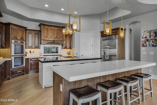 kitchen featuring dark stone counters, sink, hanging light fixtures, appliances with stainless steel finishes, and a large island