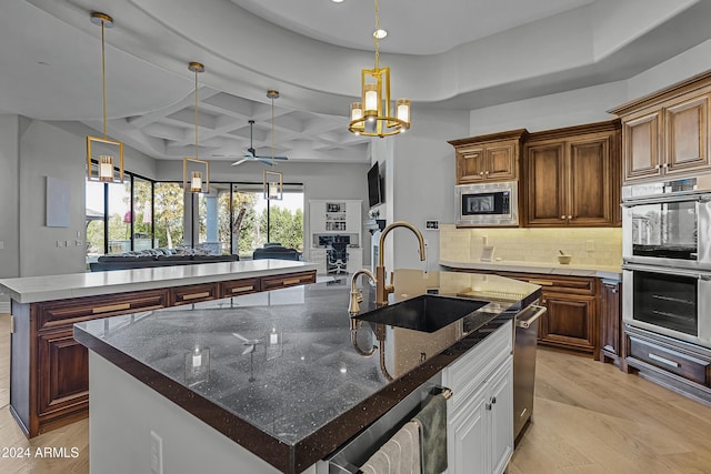 kitchen featuring sink, stainless steel appliances, coffered ceiling, a spacious island, and ceiling fan with notable chandelier