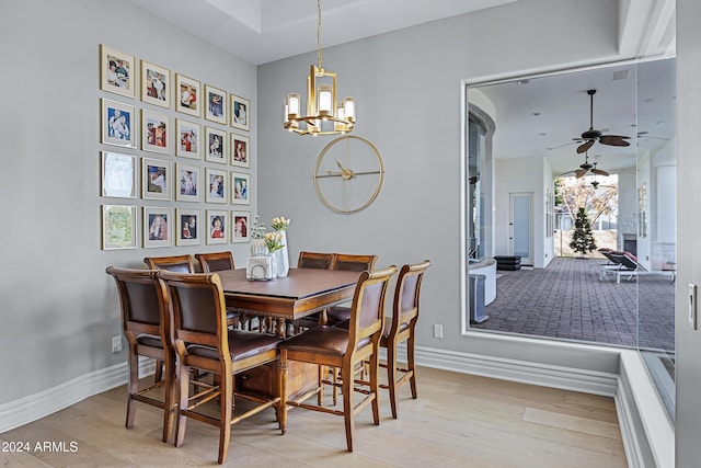 dining room featuring light wood-type flooring and ceiling fan with notable chandelier