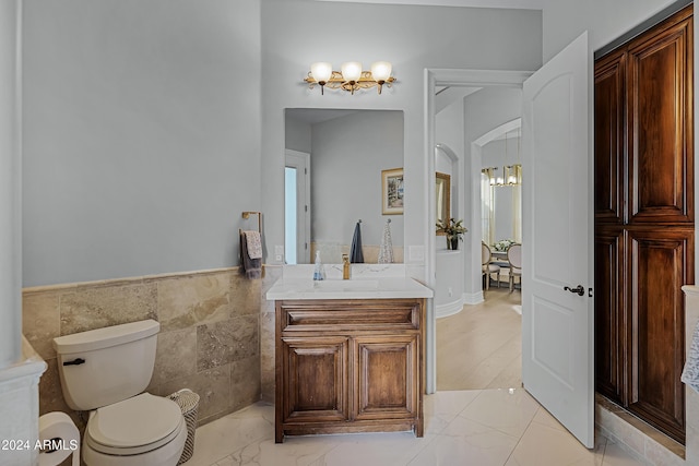 bathroom featuring vanity, toilet, and tile walls