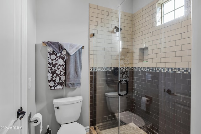 bathroom featuring a shower with shower door and toilet