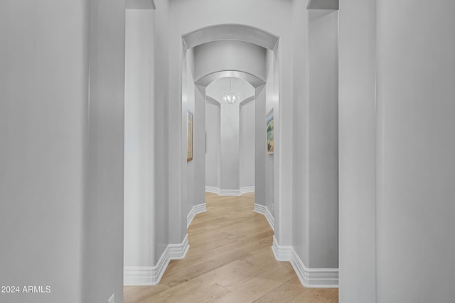 corridor with a notable chandelier and light hardwood / wood-style floors