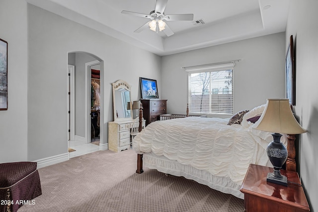 carpeted bedroom featuring a tray ceiling, ceiling fan, and a closet