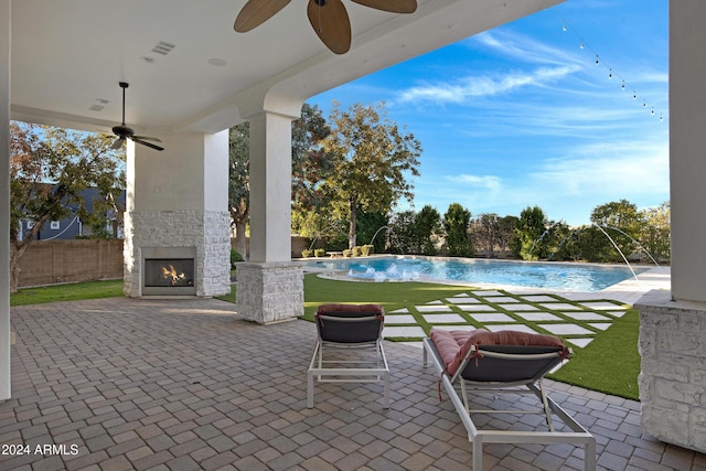 view of patio / terrace featuring pool water feature, an outdoor stone fireplace, and ceiling fan