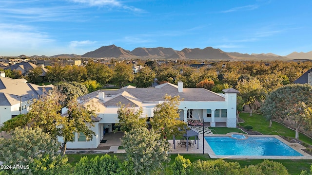 rear view of house with a patio area, a mountain view, and a yard