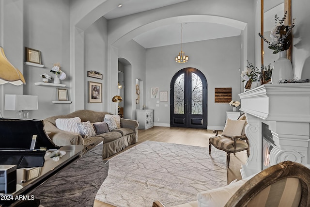 foyer with french doors, light hardwood / wood-style floors, and an inviting chandelier