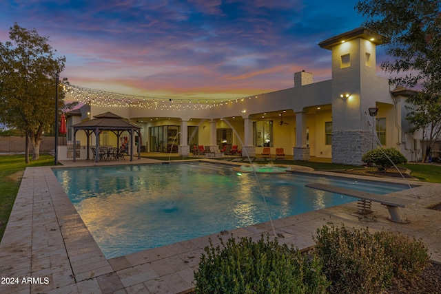 pool at dusk with a gazebo, pool water feature, and a patio