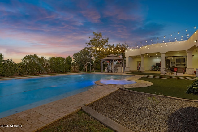 pool at dusk with a gazebo, pool water feature, and a patio